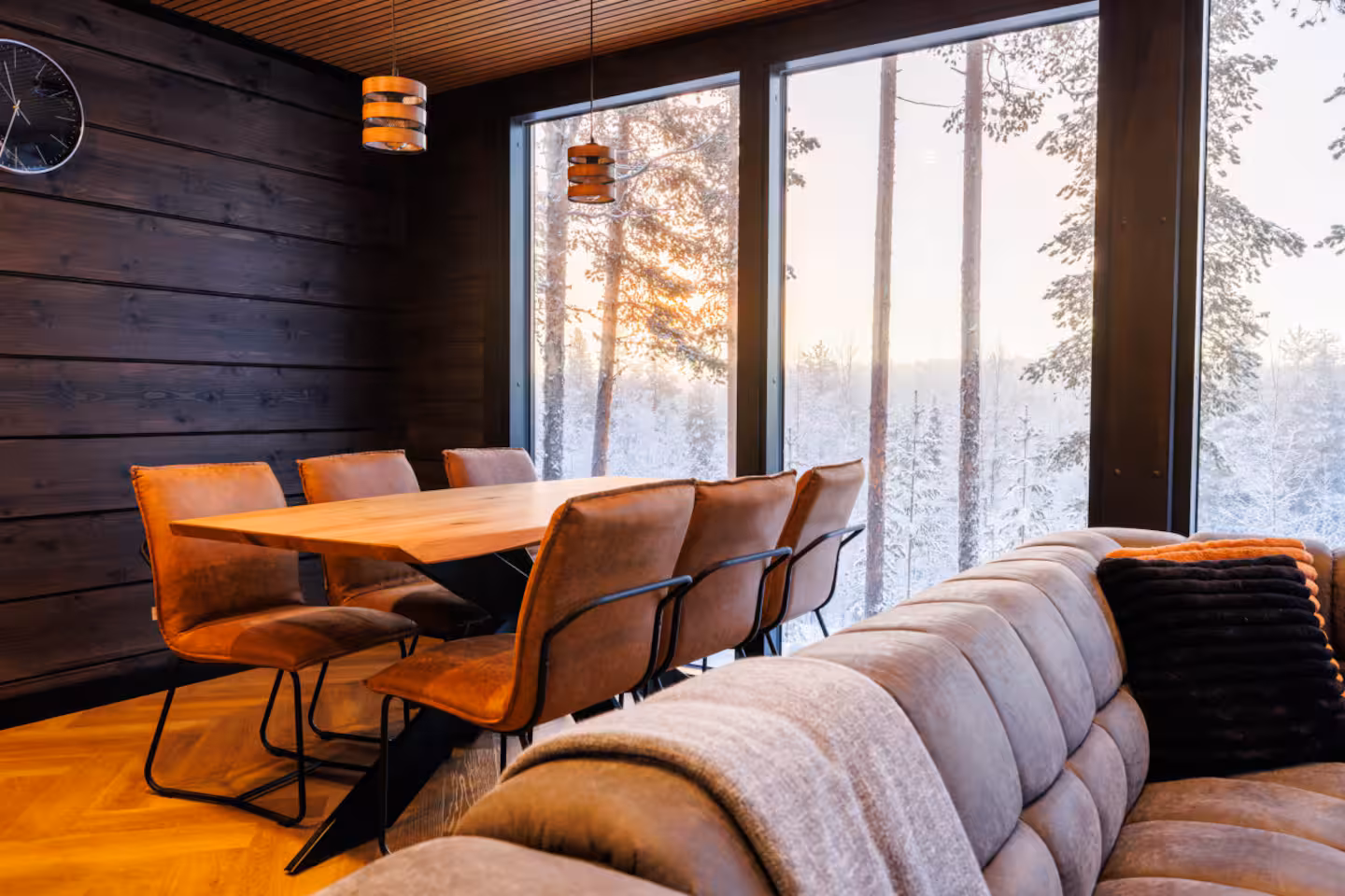 Dining table for eight beside tall windows looking onto a snowy forest