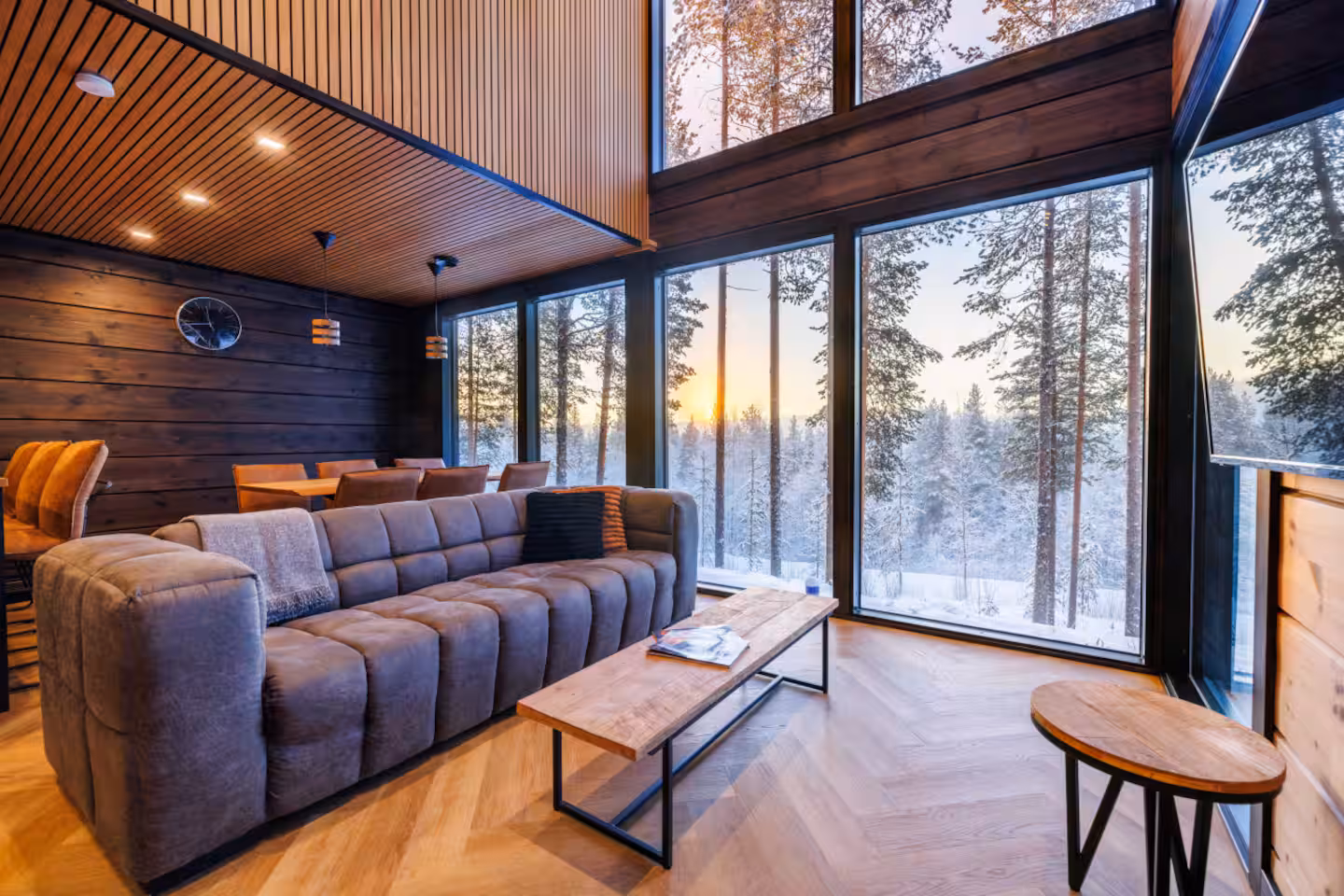Corner sofa in the double-height living room with winter sunset through the window wall