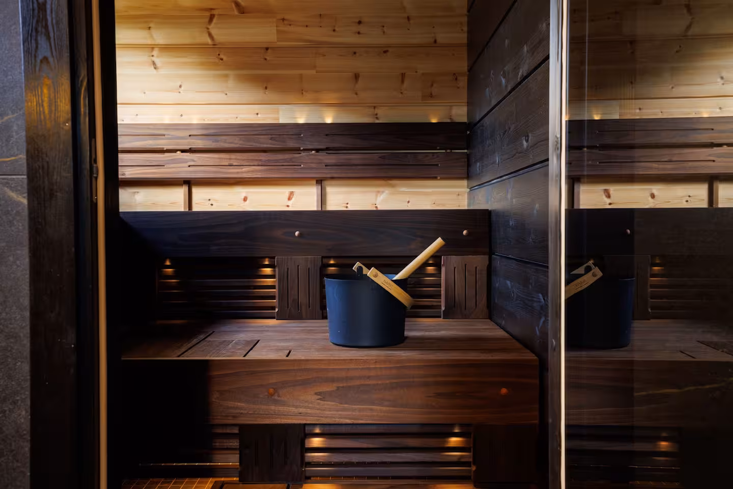 Private sauna in dark wood with a glass door opening onto the snowy terrace